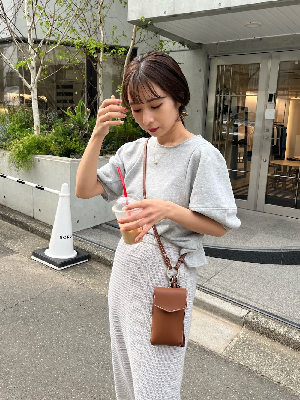 グレー系のTシャツ/カットソー、グレー系のスカート、ブラウン系のショルダーバッグを着用したレディースの春コーディネートの4枚目の写真