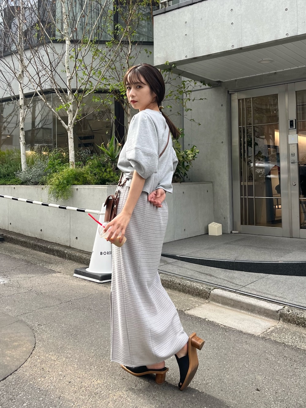 グレー系のTシャツ/カットソー、グレー系のスカート、ブラウン系のショルダーバッグを着用したレディースの春コーディネートの3枚目の写真