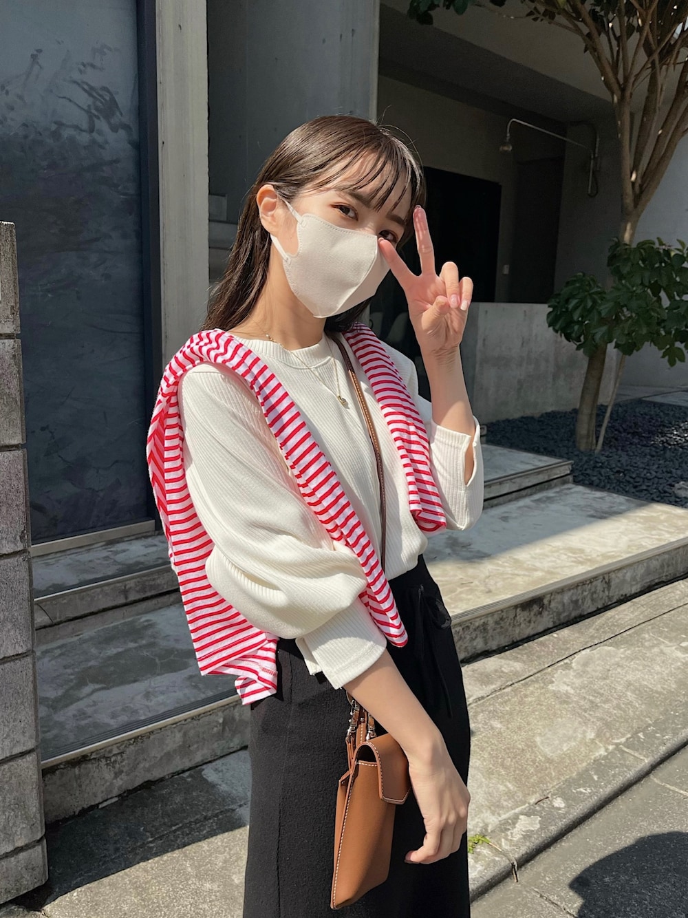 ブラック系のスカート、ブラウン系のショルダーバッグ、ブラック系のパンプスを着用したレディースの春コーディネートの3枚目の写真