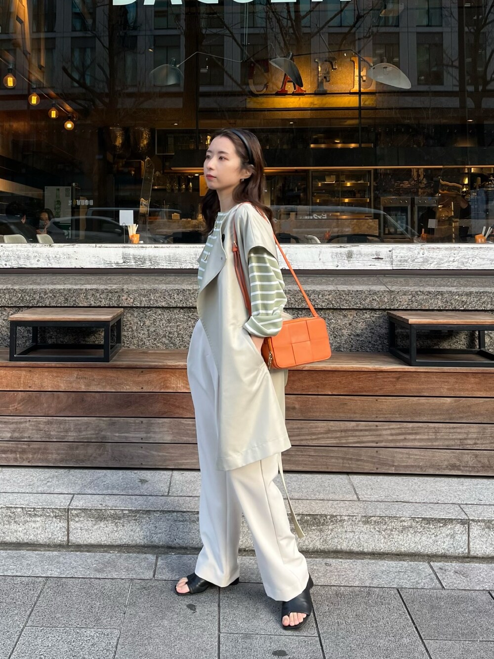 グリーン系のニット/セーター、ベージュ系のベスト、オレンジ系のショルダーバッグを着用したレディースの冬コーディネートの3枚目の写真