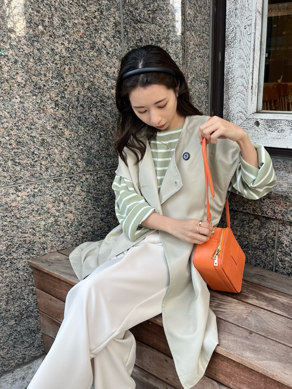 グリーン系のニット/セーター、ベージュ系のベスト、オレンジ系のショルダーバッグを着用したレディースの冬コーディネートの5枚目の写真