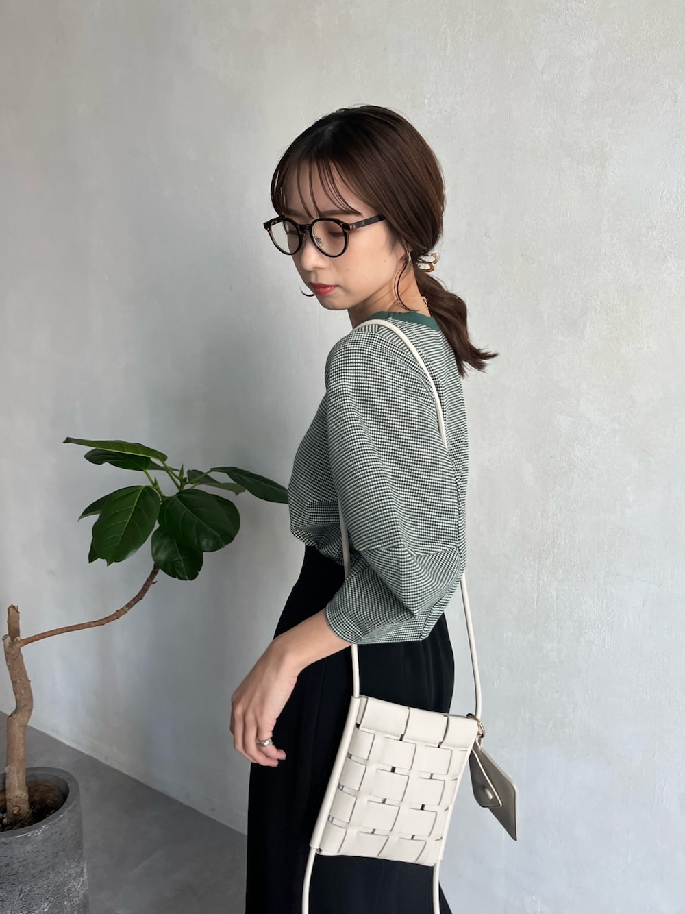 グリーン系のTシャツ/カットソー、ブラック系のスカート、ホワイト系のショルダーバッグを着用したレディースの春コーディネートの4枚目の写真