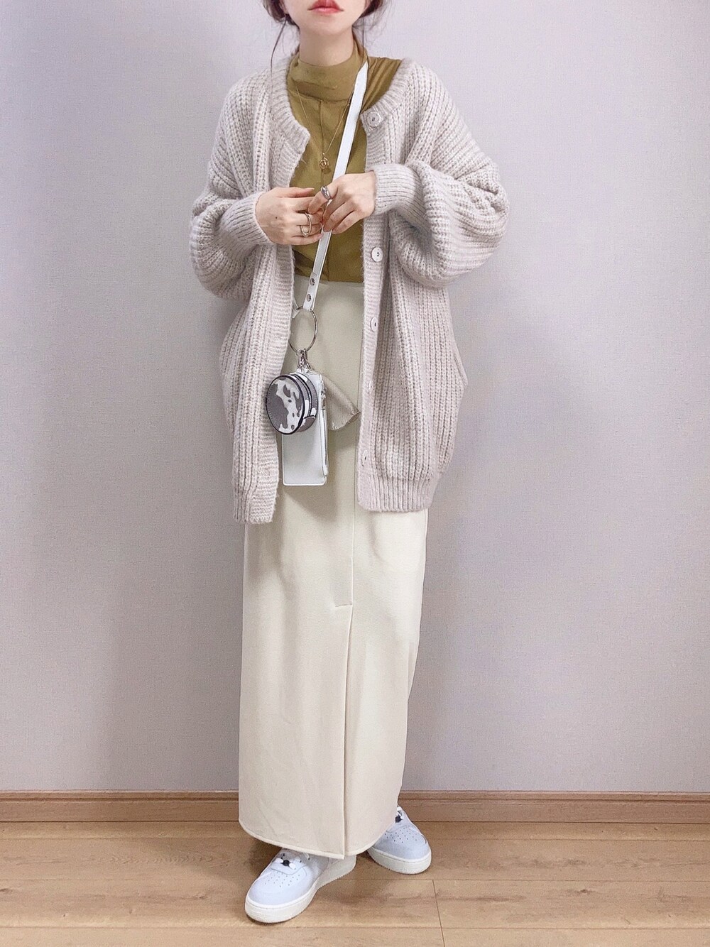 ホワイト系のカーディガン/ボレロ、ホワイト系のスカート、ホワイト系のショルダーバッグを着用したレディースの冬コーディネートの1枚目の写真