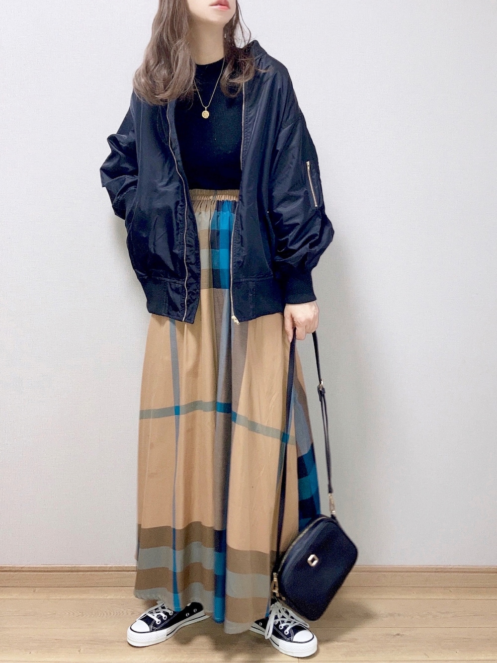 ブラック系のブルゾン、ブラック系のニット/セーター、イエロー系のスカートを着用したレディースの冬コーディネートの1枚目の写真