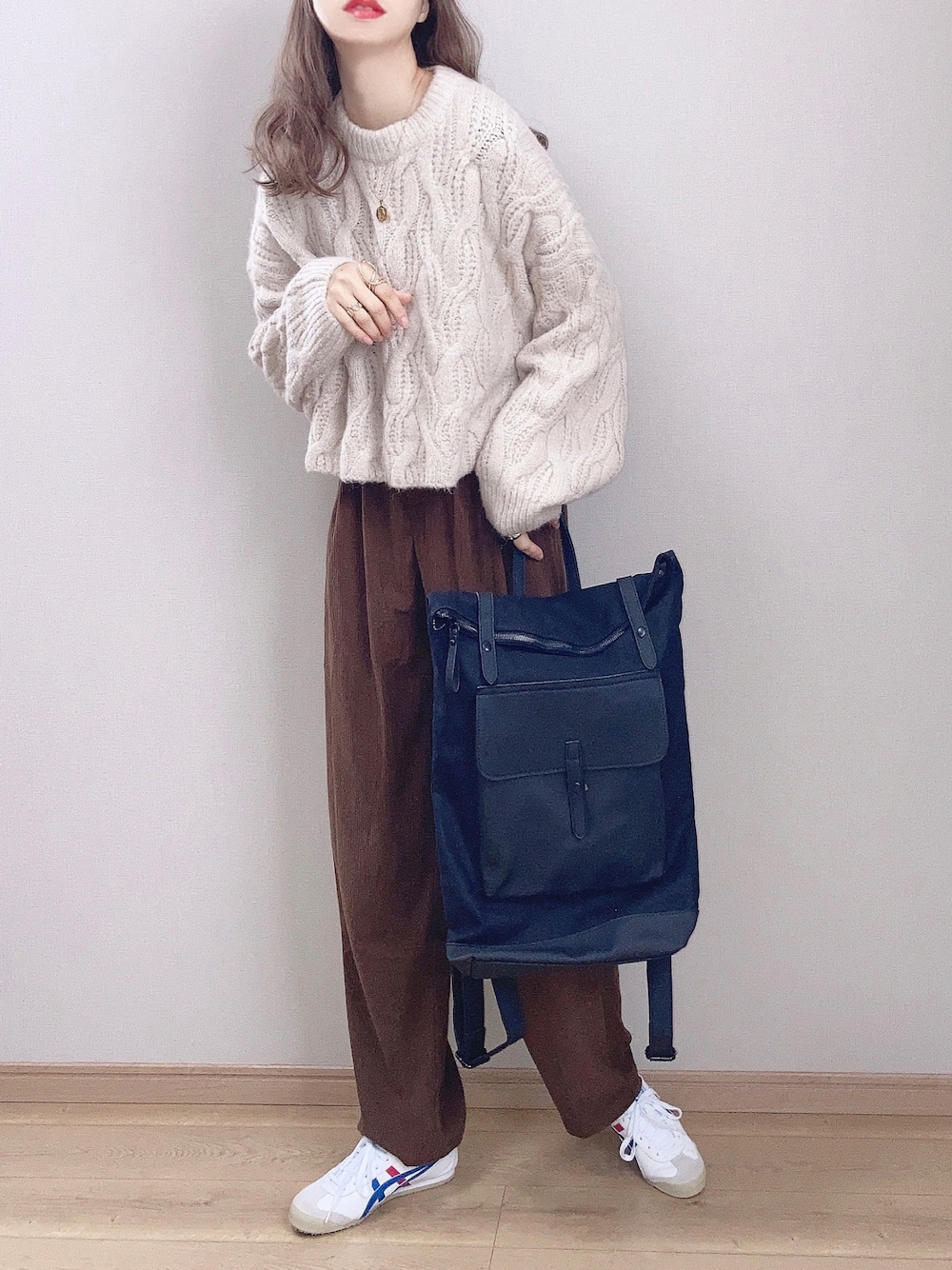 ホワイト系のスニーカー、ホワイト系のニット/セーター、ブラウン系のその他パンツを着用したレディースの秋コーディネートの1枚目の写真