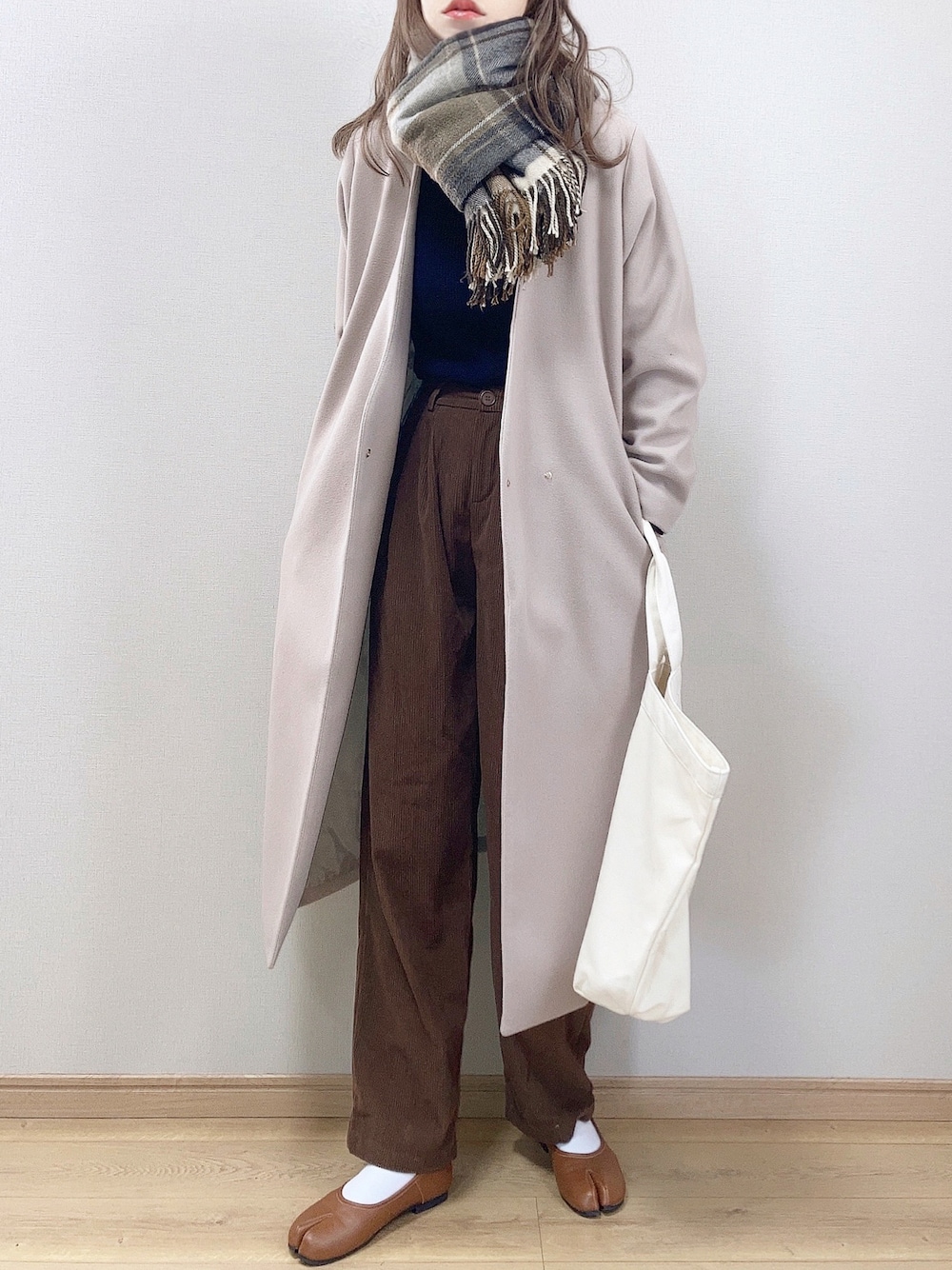 グレー系のノーカラーコート、ホワイト系のトートバッグ、ブラウン系のその他パンツを着用したレディースの冬コーディネートの1枚目の写真