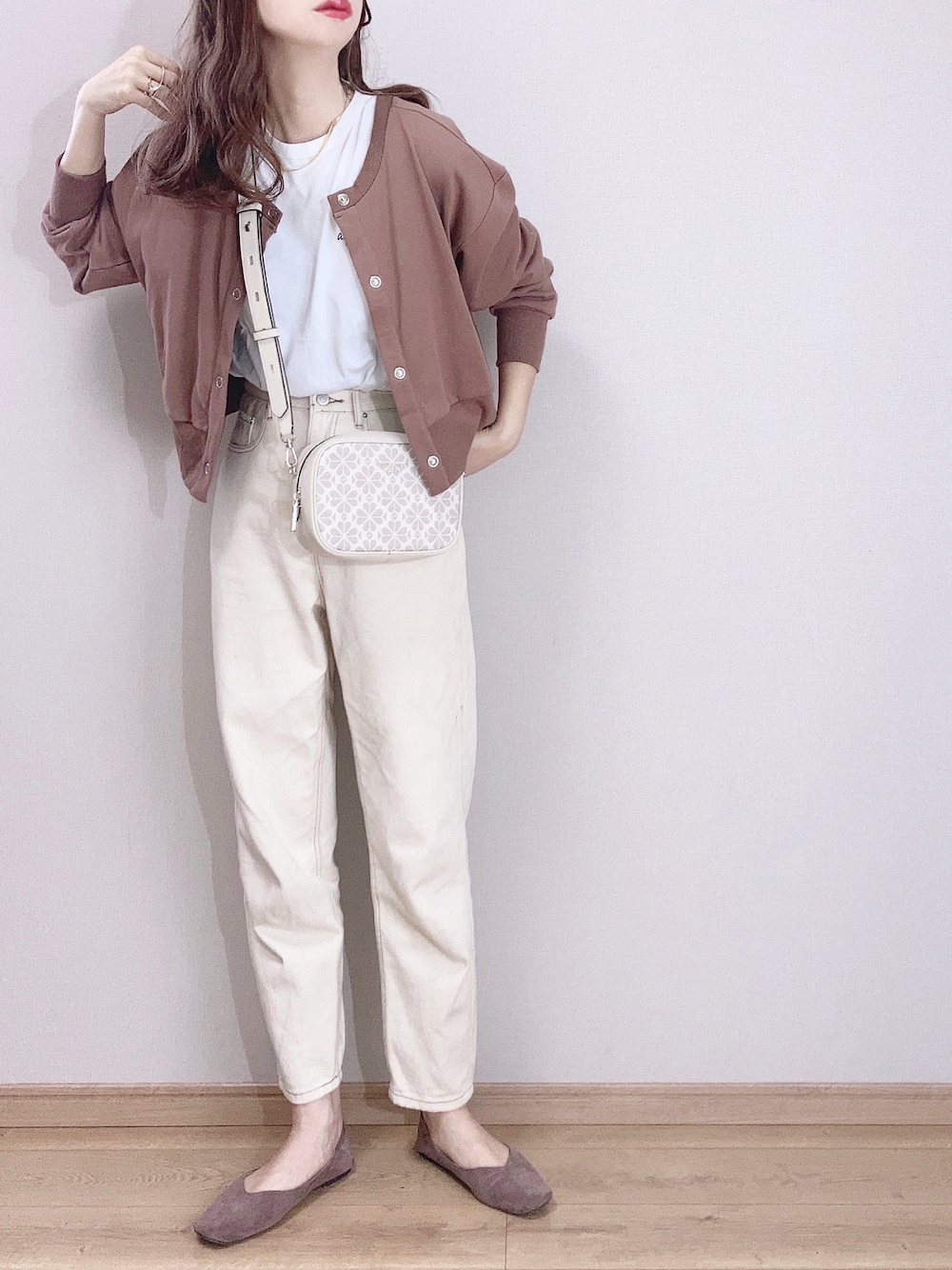 ホワイト系のショルダーバッグ、ブラウン系のカーディガン/ボレロ、ホワイト系のTシャツ/カットソーを着用したレディースの春コーディネートの1枚目の写真