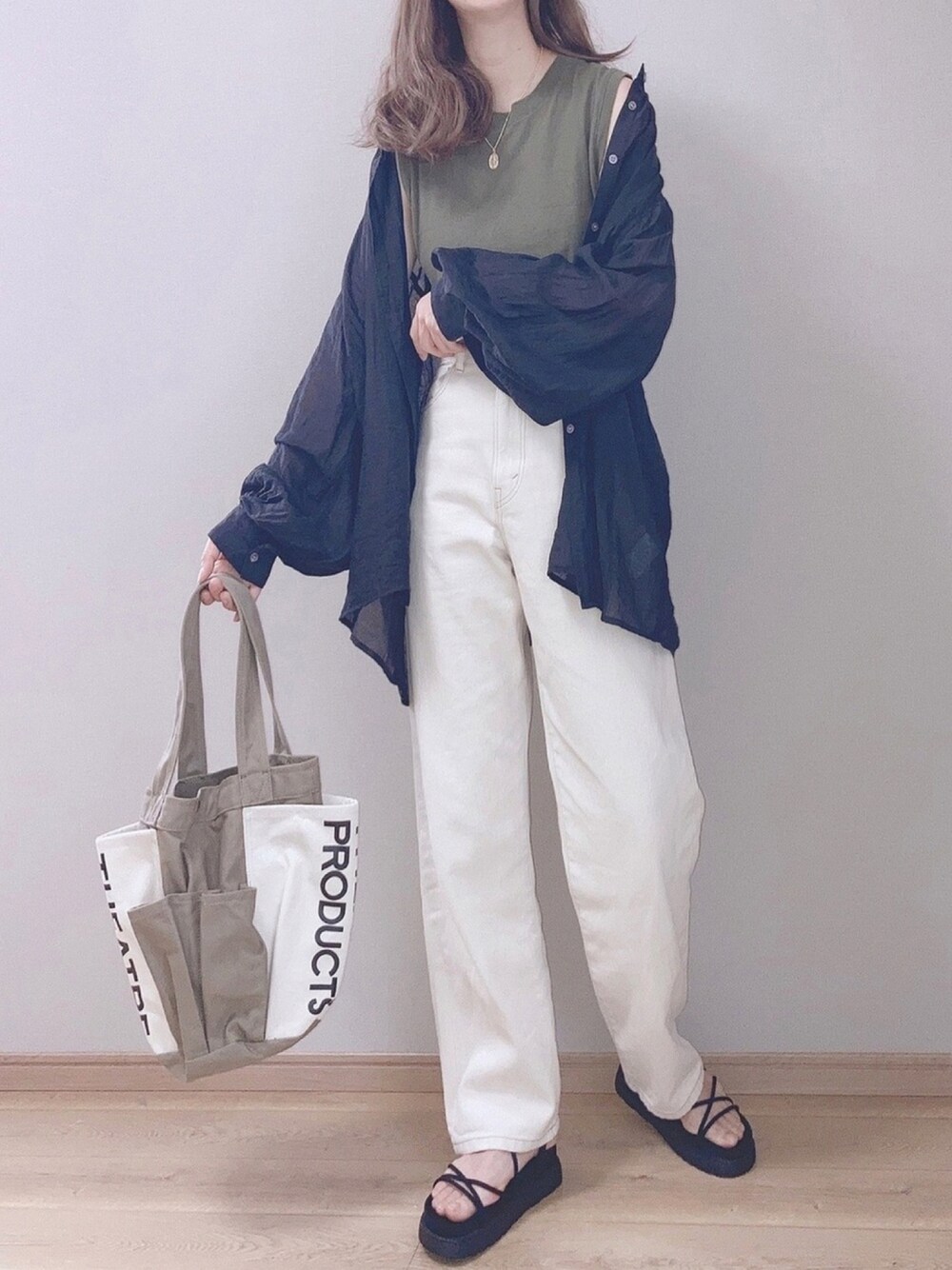 イエロー系のトートバッグ、ブラック系のシャツ/ブラウス、ホワイト系のデニムパンツを着用したレディースの春コーディネートの1枚目の写真