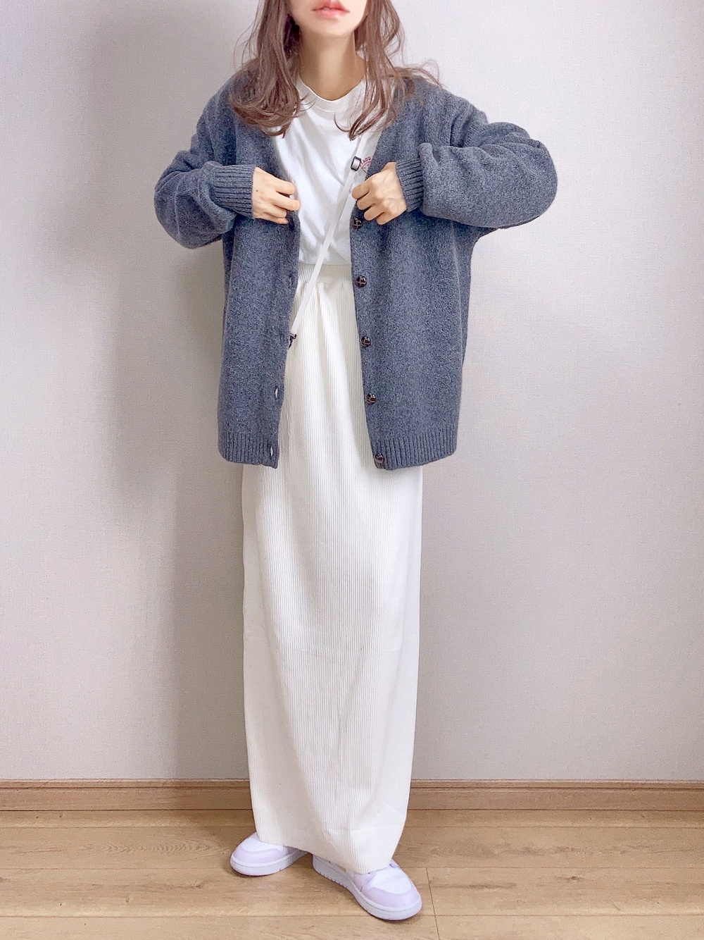 グレー系のカーディガン/ボレロ、ホワイト系のスカート、パープル系のスニーカーを着用したレディースの冬コーディネートの1枚目の写真