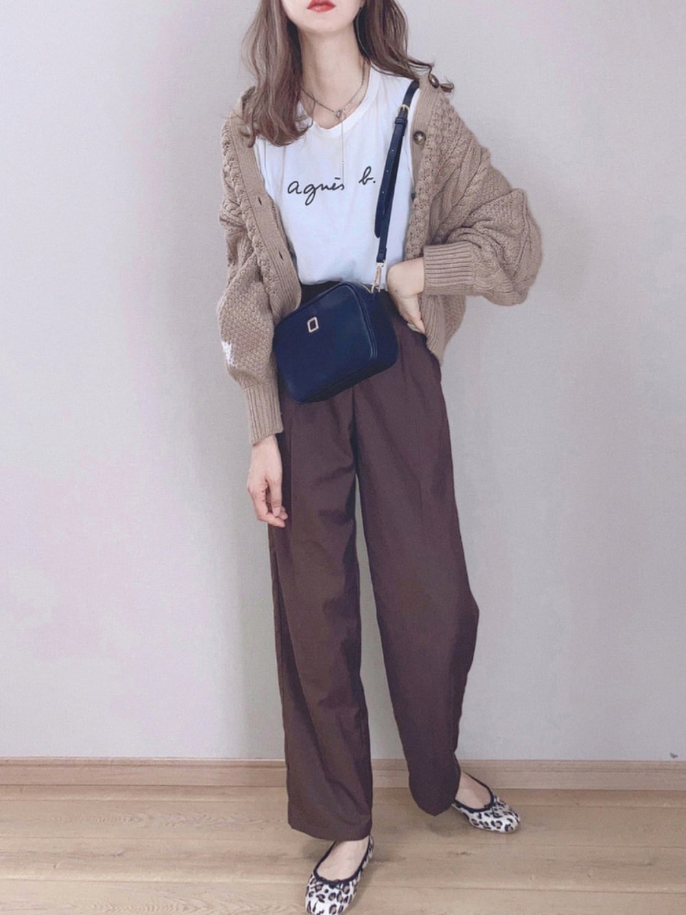 ブラック系のショルダーバッグ、ベージュ系のカーディガン/ボレロ、ホワイト系のTシャツ/カットソーを着用したレディースの秋コーディネートの1枚目の写真