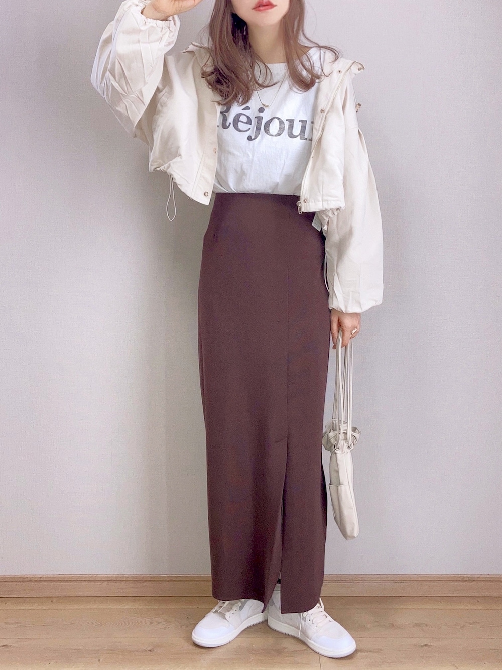 ホワイト系のマウンテンパーカー、ホワイト系のTシャツ/カットソー、ブラウン系のスカートを着用したレディースの春コーディネートの1枚目の写真