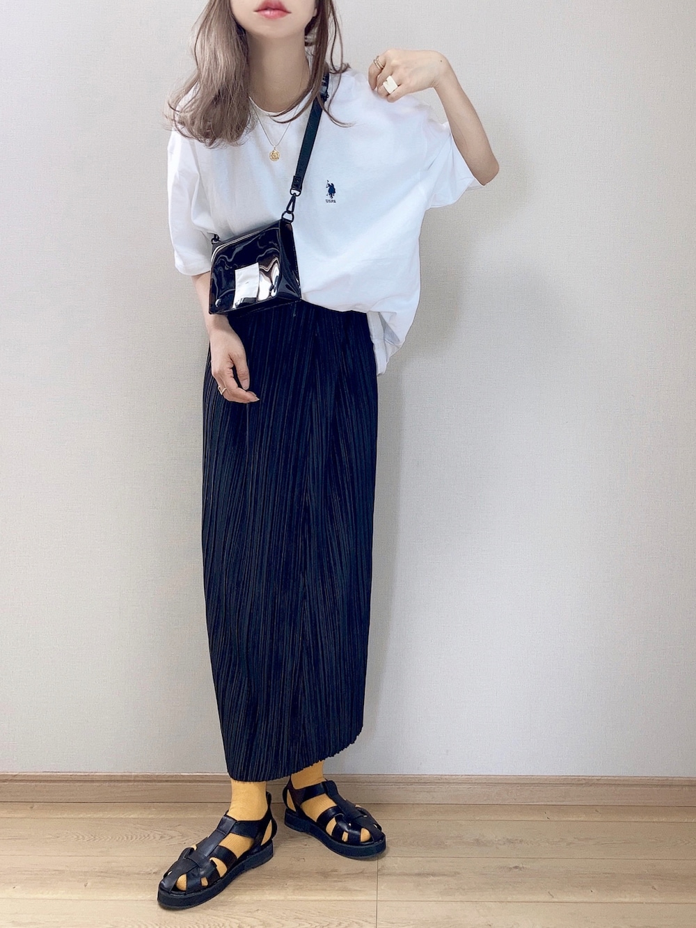 ブラック系のサンダル、ホワイト系のTシャツ/カットソー、ブラック系のスカートを着用したレディースの夏コーディネートの1枚目の写真