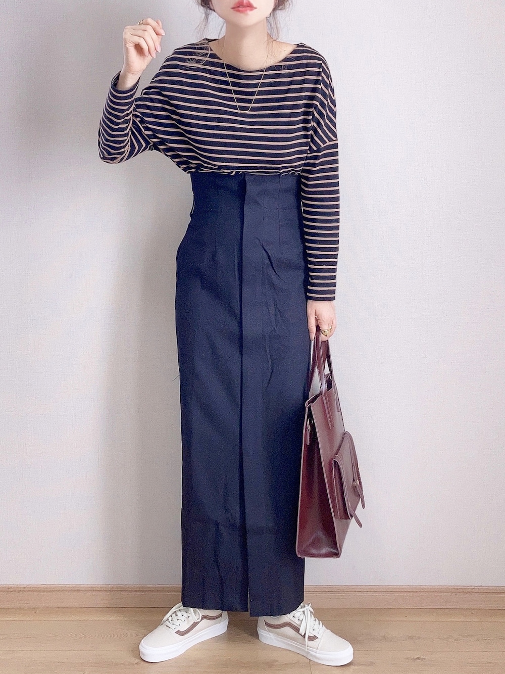 ブラック系のTシャツ/カットソー、ブラック系のスカート、ブラウン系のハンドバッグを着用したレディースの秋コーディネートの1枚目の写真