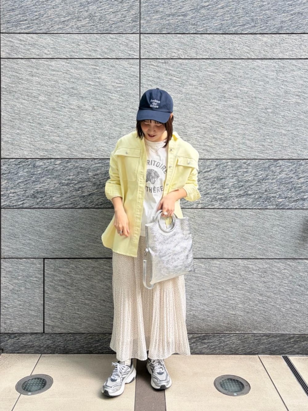 ホワイト系のスカート、ホワイト系のTシャツ/カットソー、シルバー系のハンドバッグを着用したレディースの冬コーディネートの1枚目の写真