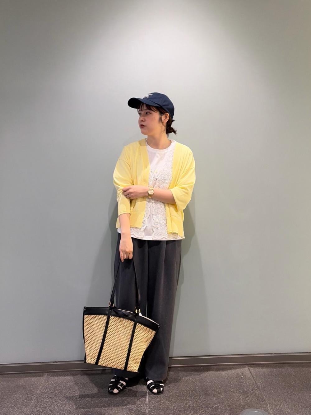 ブラック系のトートバッグ、イエロー系のカーディガン/ボレロ、ホワイト系のベストを着用したレディースの春コーディネートの1枚目の写真