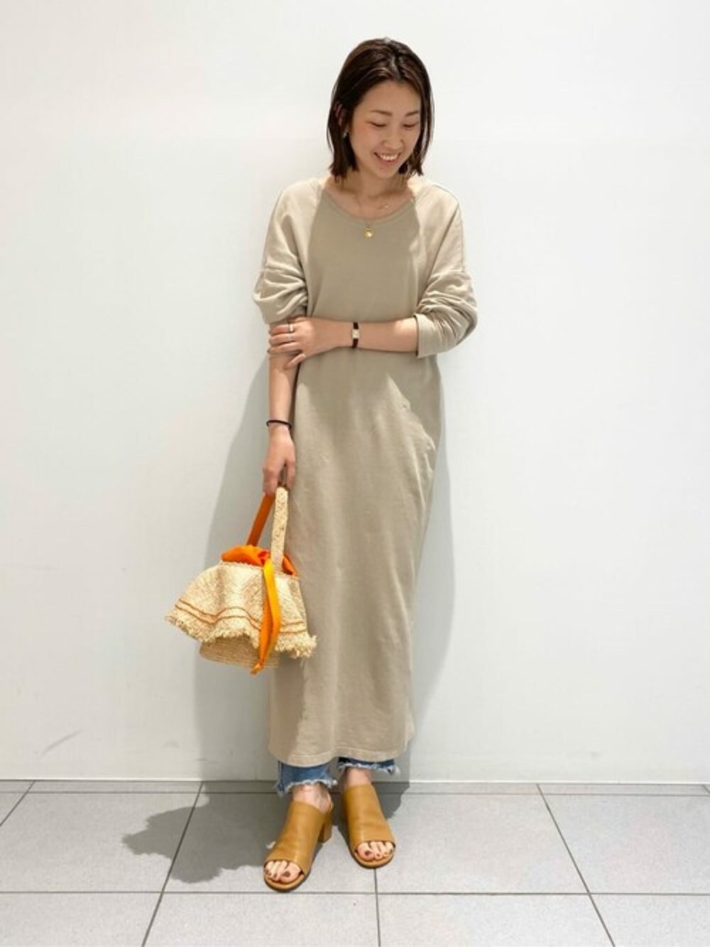 イエロー系のサンダル、オレンジ系のかごバッグを着用したレディースの春コーディネートの1枚目の写真