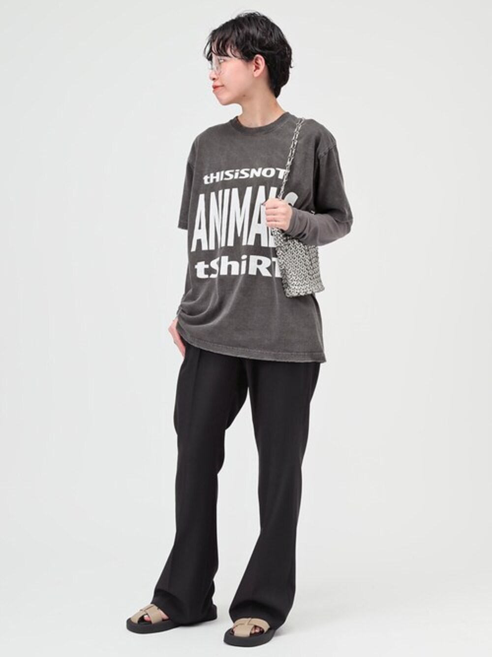 ブラック系のスラックス、グレー系のTシャツ/カットソー、ベージュ系のサンダルを着用したレディースの春コーディネートの1枚目の写真