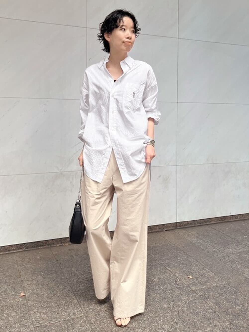 ベージュ系のその他パンツ、ホワイト系のシャツ/ブラウス、ブラック系のショルダーバッグを着用したレディースの春コーディネートの1枚目の写真