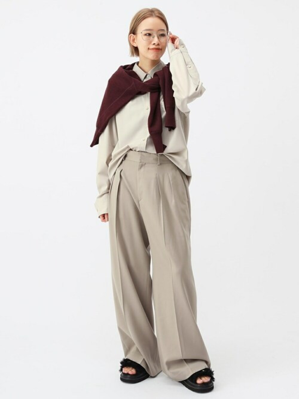 ベージュ系のスラックス、ブラック系のサンダル、レッド系のニット/セーターを着用したレディースの夏コーディネートの1枚目の写真