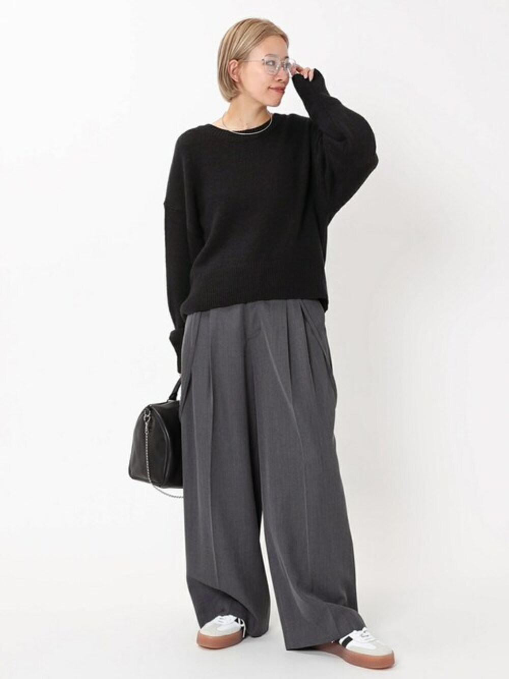 グレー系のスラックス、ブラック系のニット/セーターを着用したレディースの秋コーディネートの1枚目の写真