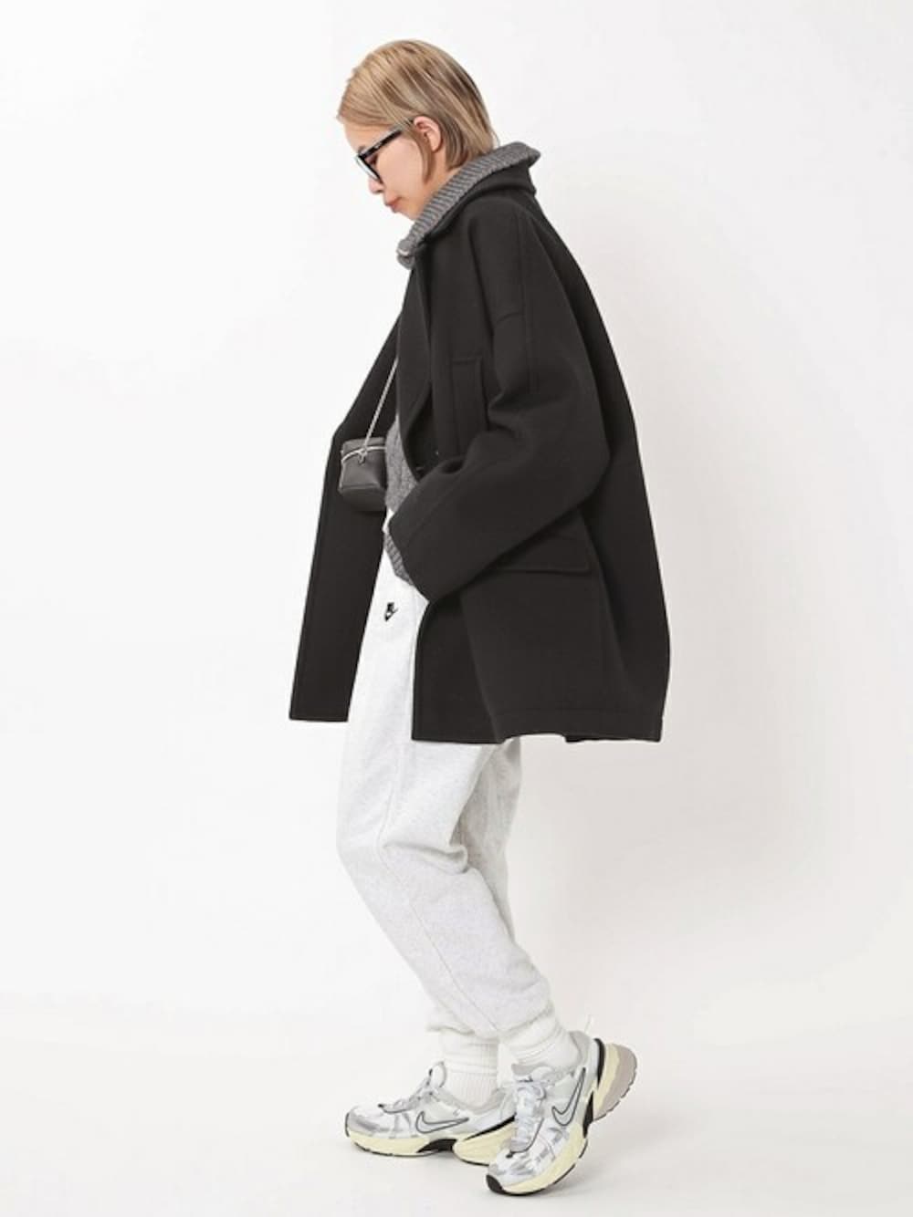 ブラック系のピーコート、ホワイト系のスウェットパンツ、グレー系のニット/セーターを着用したレディースの冬コーディネートの1枚目の写真