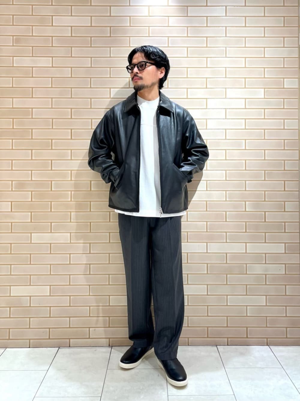ブラック系のその他アウター、ホワイト系のTシャツ/カットソー、グレー系のその他パンツを着用したメンズの秋コーディネートの1枚目の写真