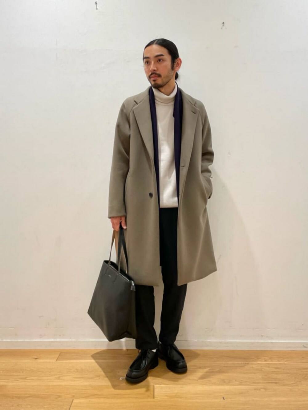 ブラウン系のチェスターコート、グレー系のニット/セーター、ブルー系のその他パンツを着用したメンズの冬コーディネートの1枚目の写真