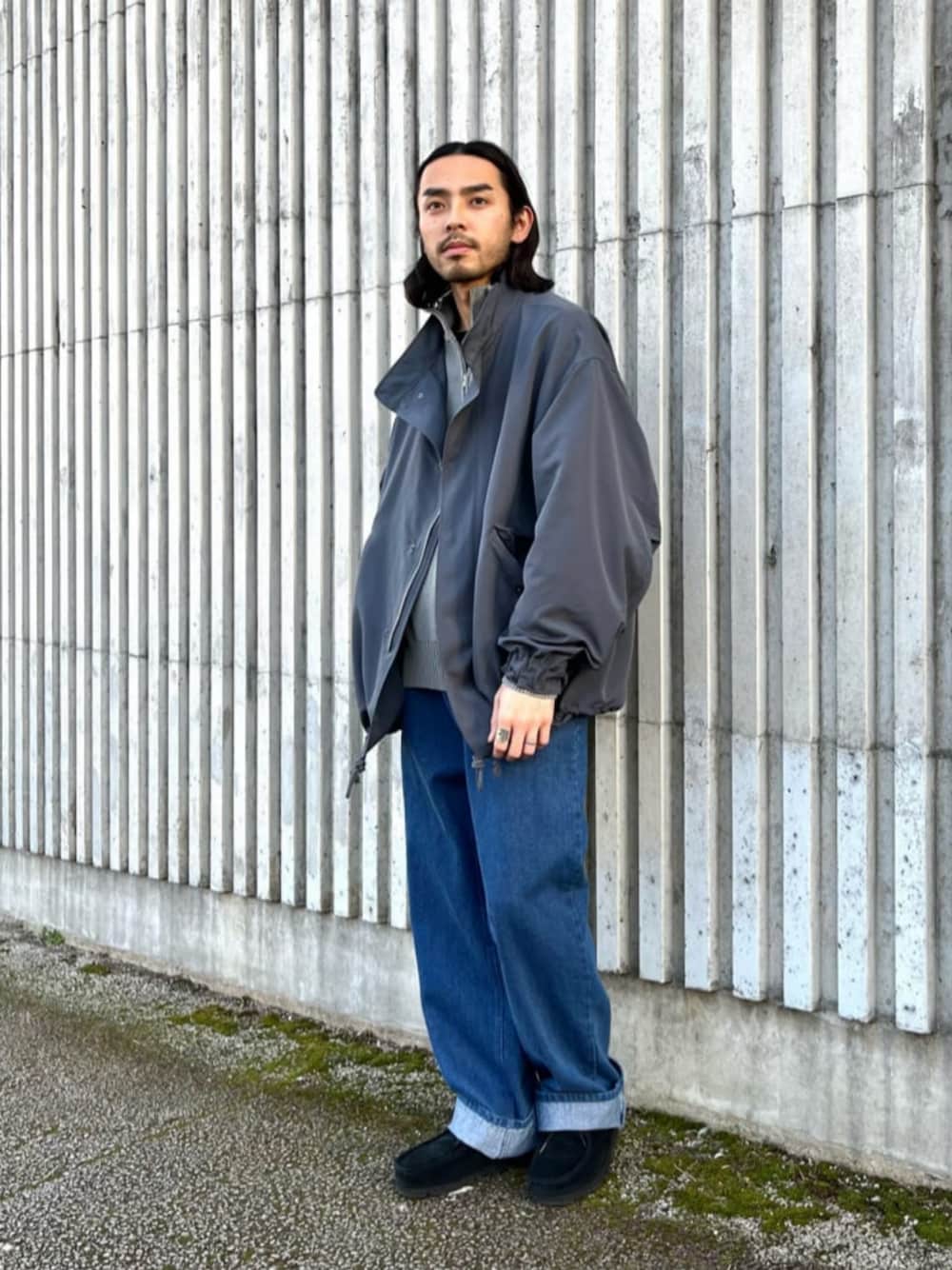 グレー系のモッズコート、グレー系のニット/セーター、ブルー系のデニムパンツを着用したメンズの冬コーディネートの1枚目の写真