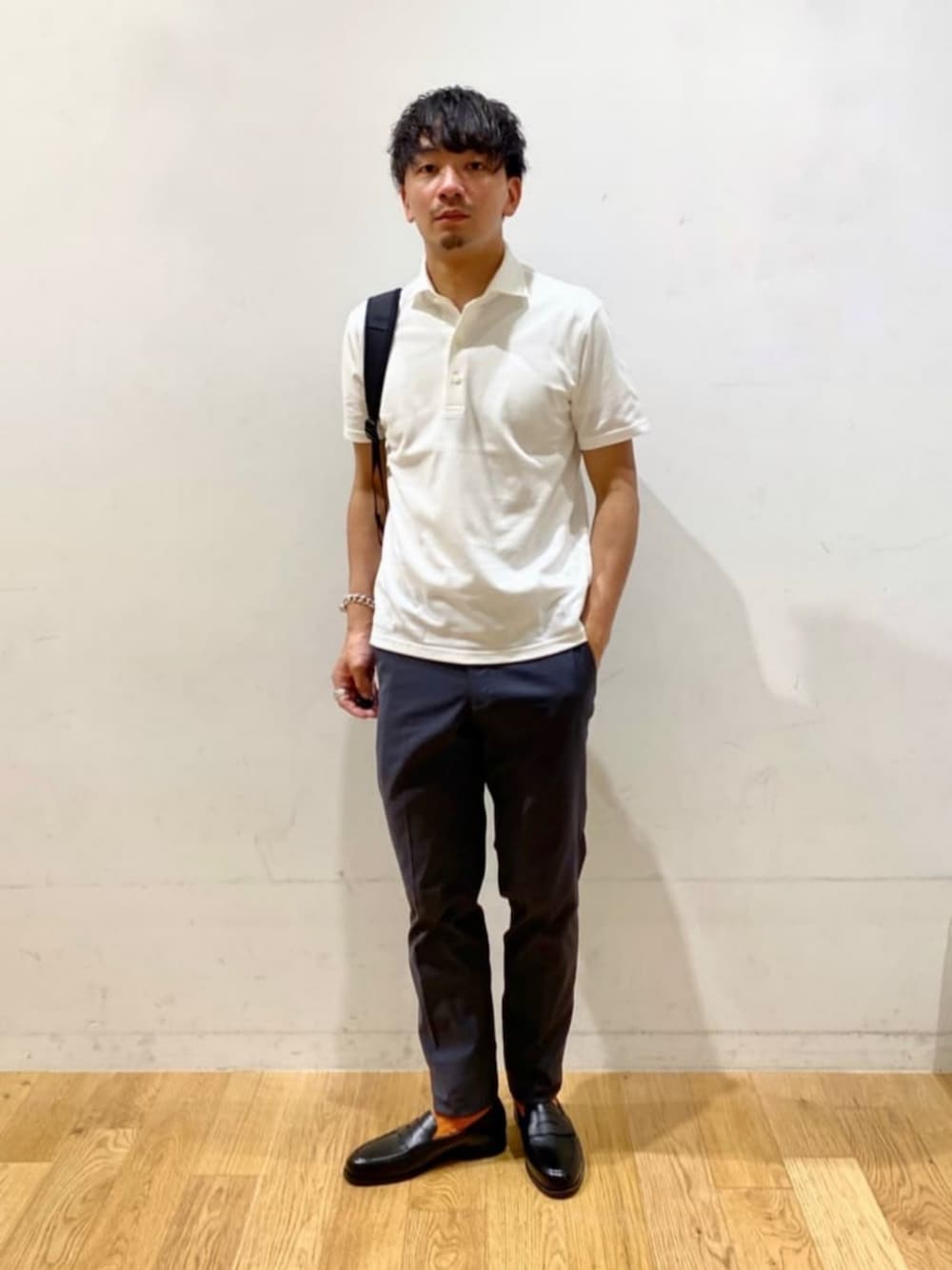 ブラック系のローファー、グレー系のスラックス、ホワイト系のポロシャツを着用したメンズの夏コーディネートの1枚目の写真