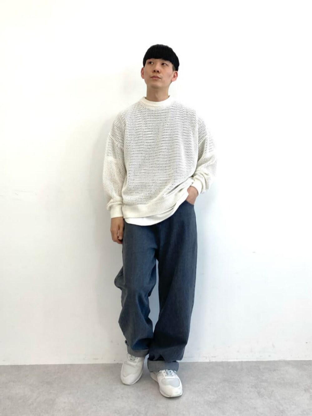 グレー系のスニーカー、ホワイト系のニット/セーター、グレー系のデニムパンツを着用したメンズの冬コーディネートの1枚目の写真