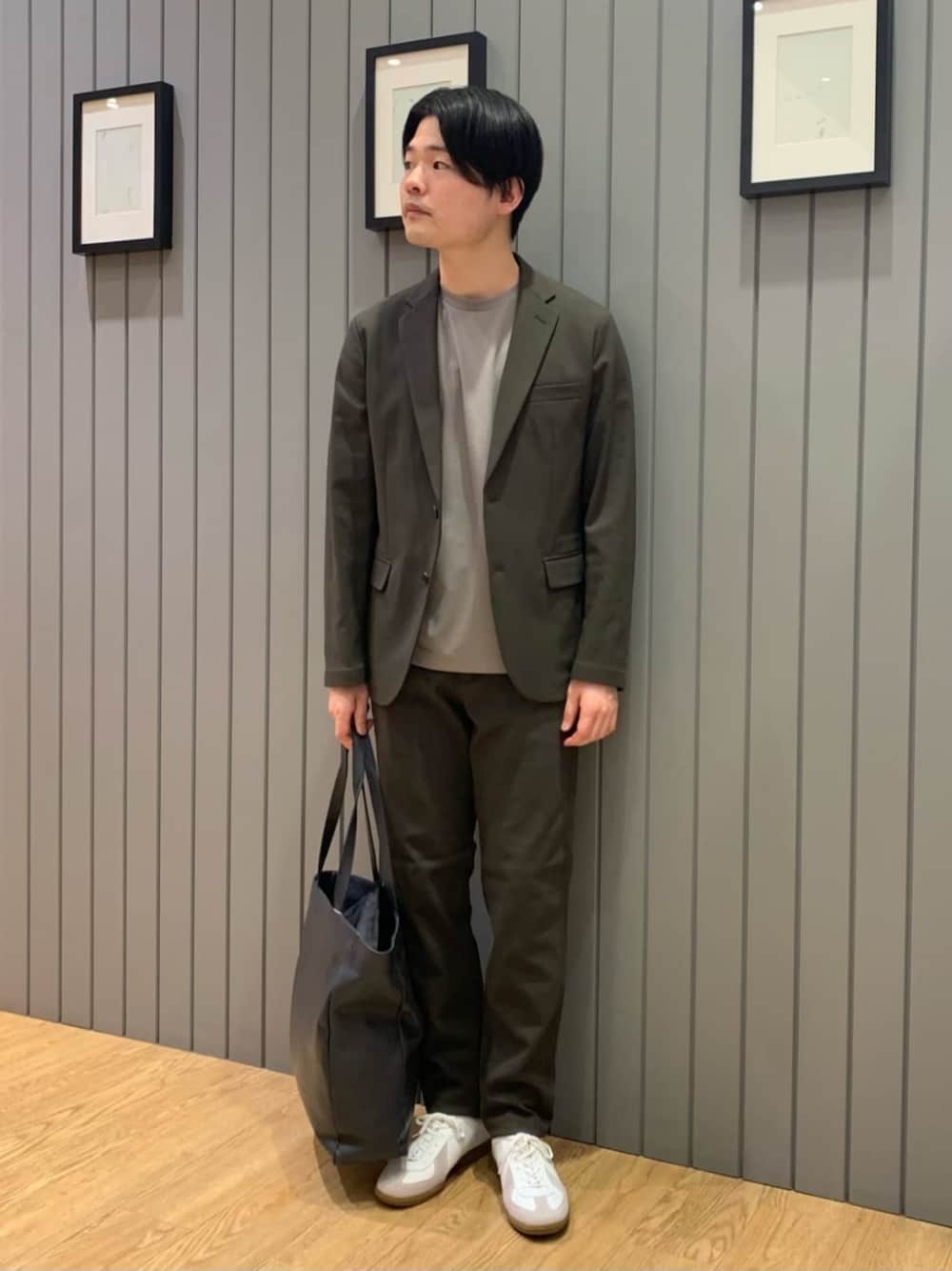 ブルー系のトートバッグ、ホワイト系のスニーカー、グリーン系のテーラードジャケットを着用したメンズの冬コーディネートの1枚目の写真