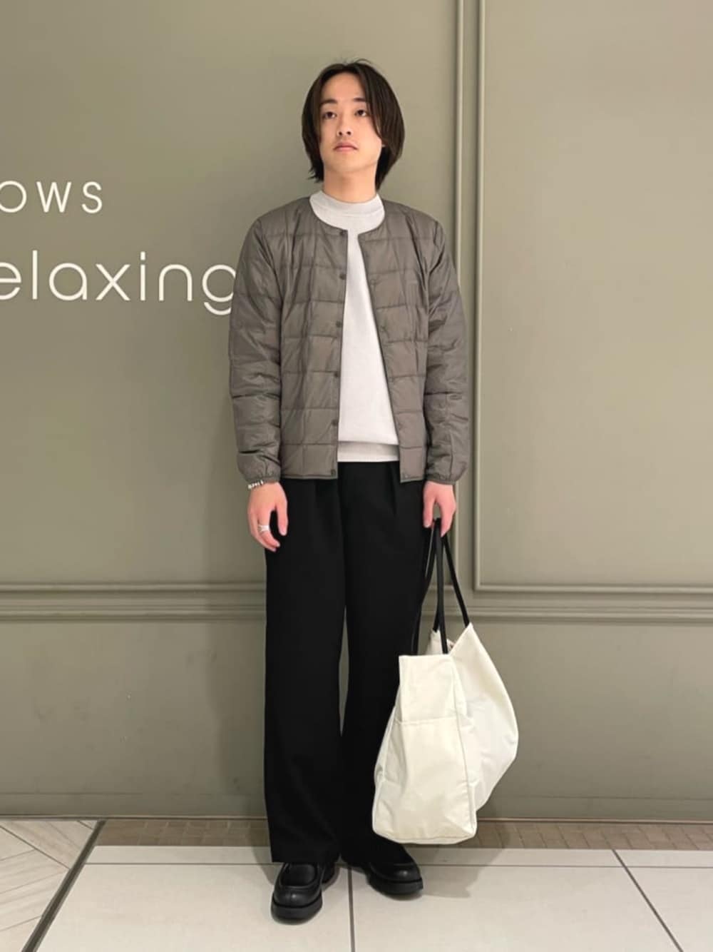 ブラック系のチノパンツ、ベージュ系のトートバッグ、グレー系のダウンジャケット/コートを着用したメンズの冬コーディネートの1枚目の写真