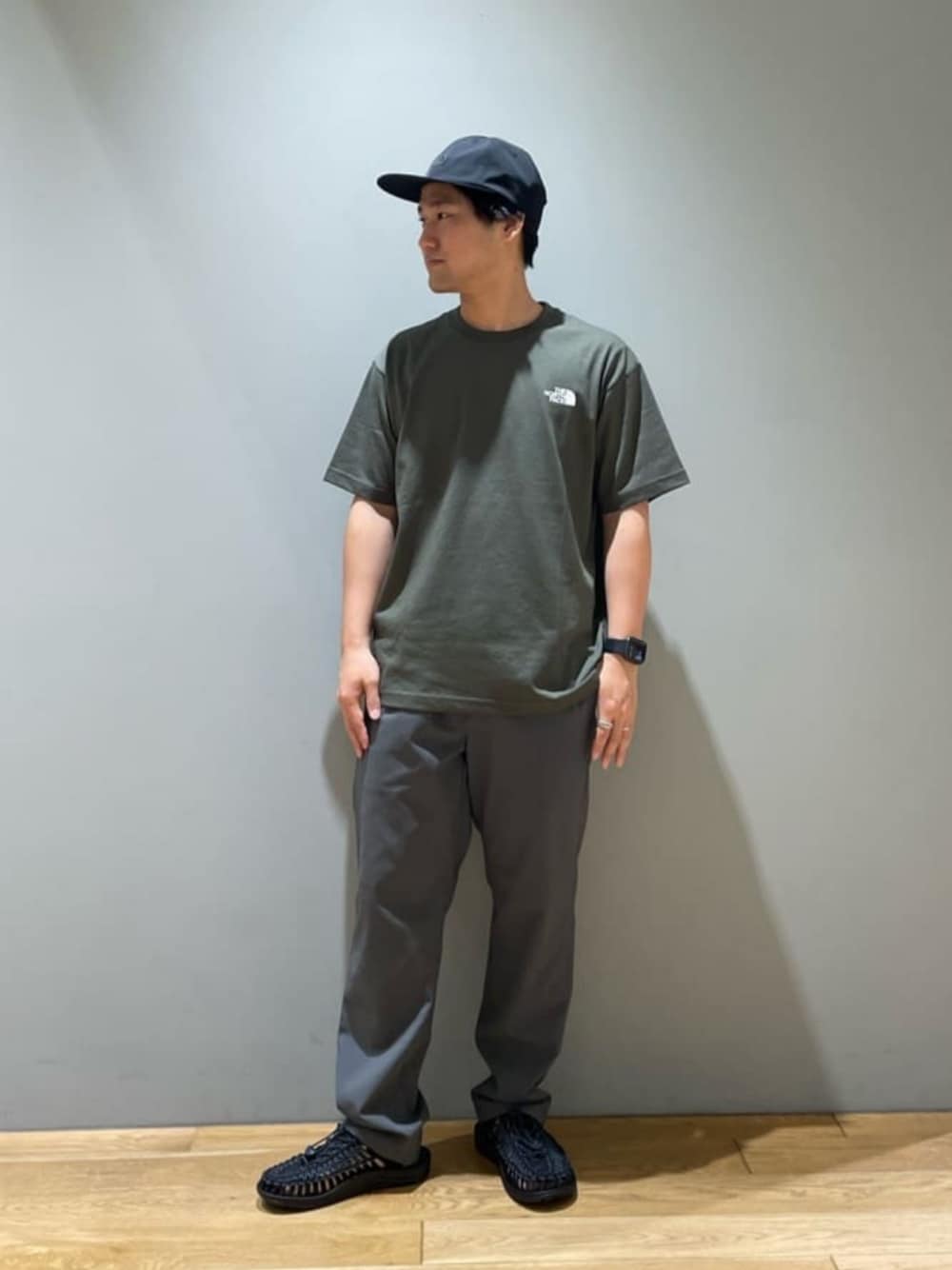 グリーン系のTシャツ/カットソー、グレー系のその他パンツ、ブラック系のサンダルを着用したメンズの春コーディネートの1枚目の写真