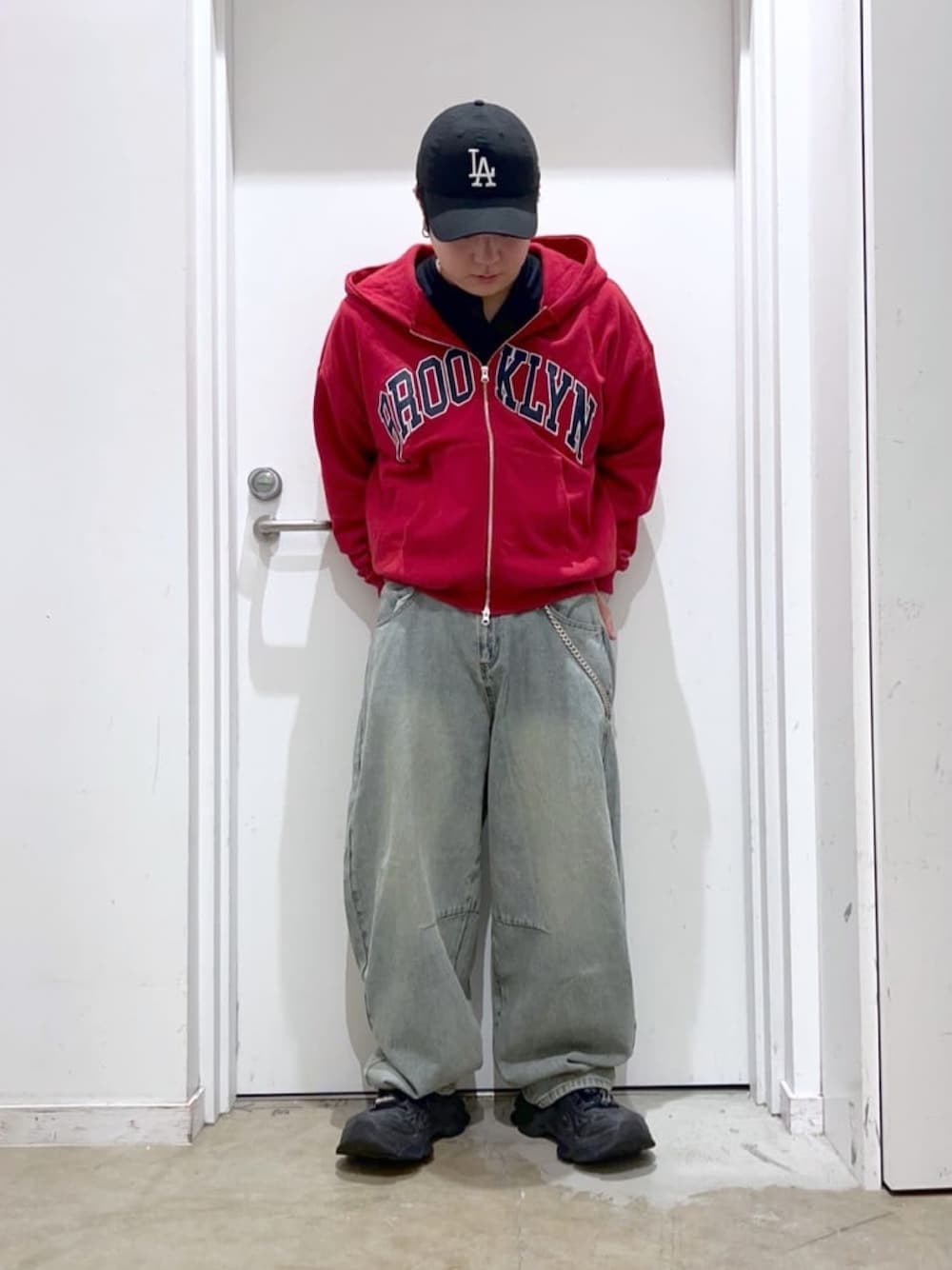 ブルー系のデニムパンツ、レッド系のパーカー、ブラック系のTシャツ/カットソーを着用したメンズの春コーディネートの1枚目の写真