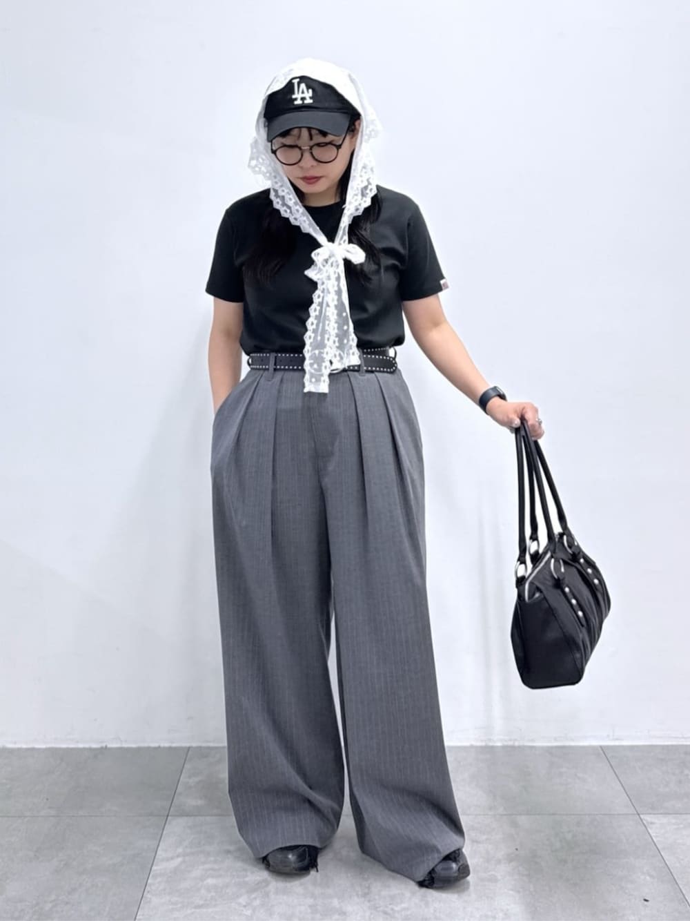 グレー系のスラックス、ブラック系のハンドバッグ、ブラック系のTシャツ/カットソーを着用したレディースの夏コーディネートの1枚目の写真