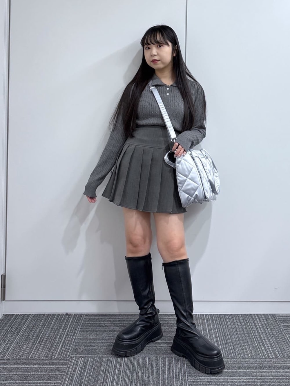 グレー系のニット/セーター、グレー系のスカート、ブラック系のブーツを着用したレディースの秋コーディネートの1枚目の写真