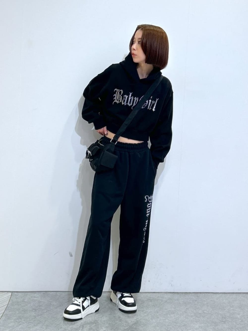 ブラック系のショルダーバッグ、ブラック系のスウェット、ブラック系のスウェットパンツを着用したレディースの冬コーディネートの1枚目の写真