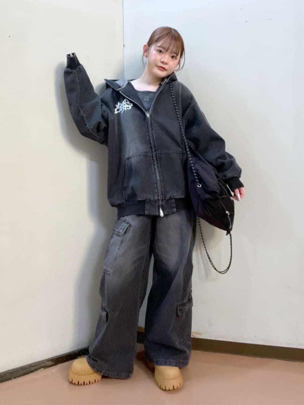 イエロー系のブーツ、ブラック系のデニムジャケット、ブラック系のカーゴパンツを着用したレディースの冬コーディネートの1枚目の写真