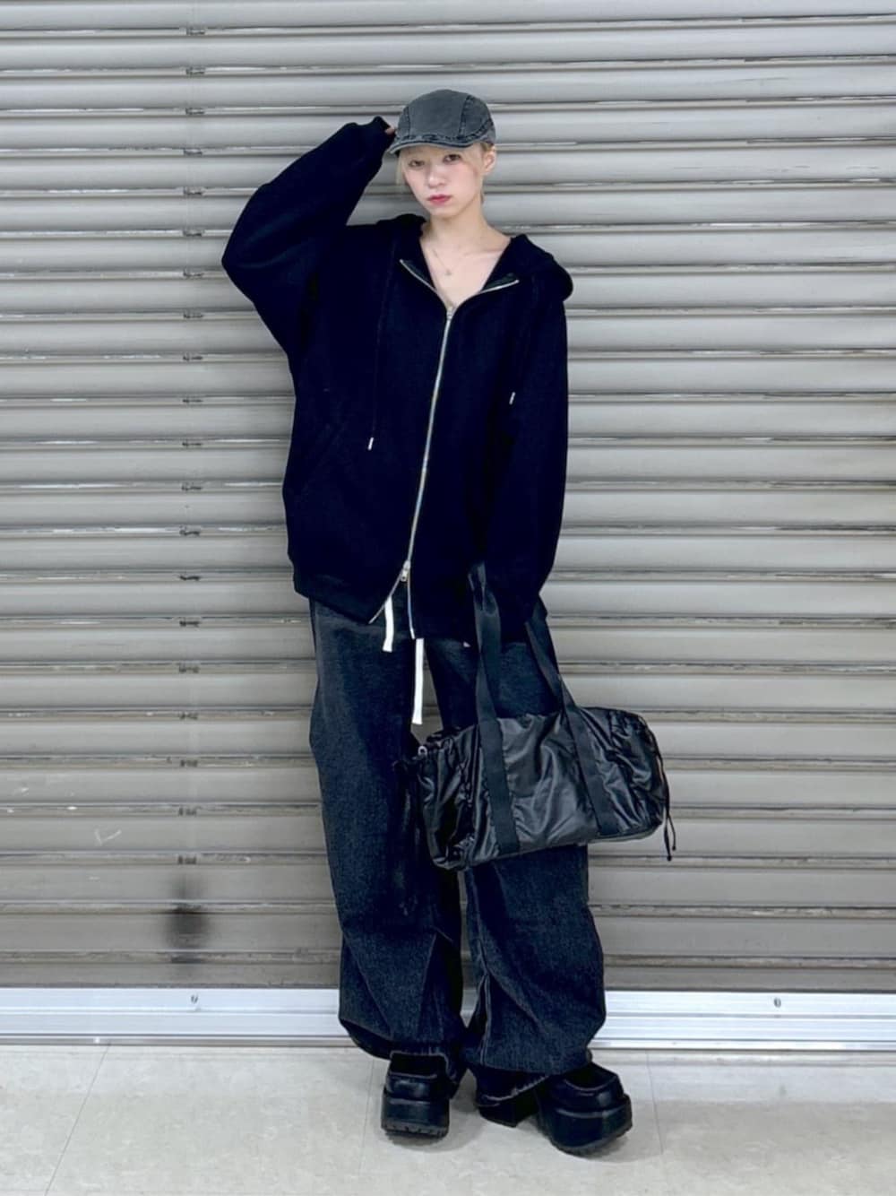 ブラック系のデニムパンツ、ブラック系のボストンバッグ、ブラック系のパーカーを着用したレディースの冬コーディネートの1枚目の写真