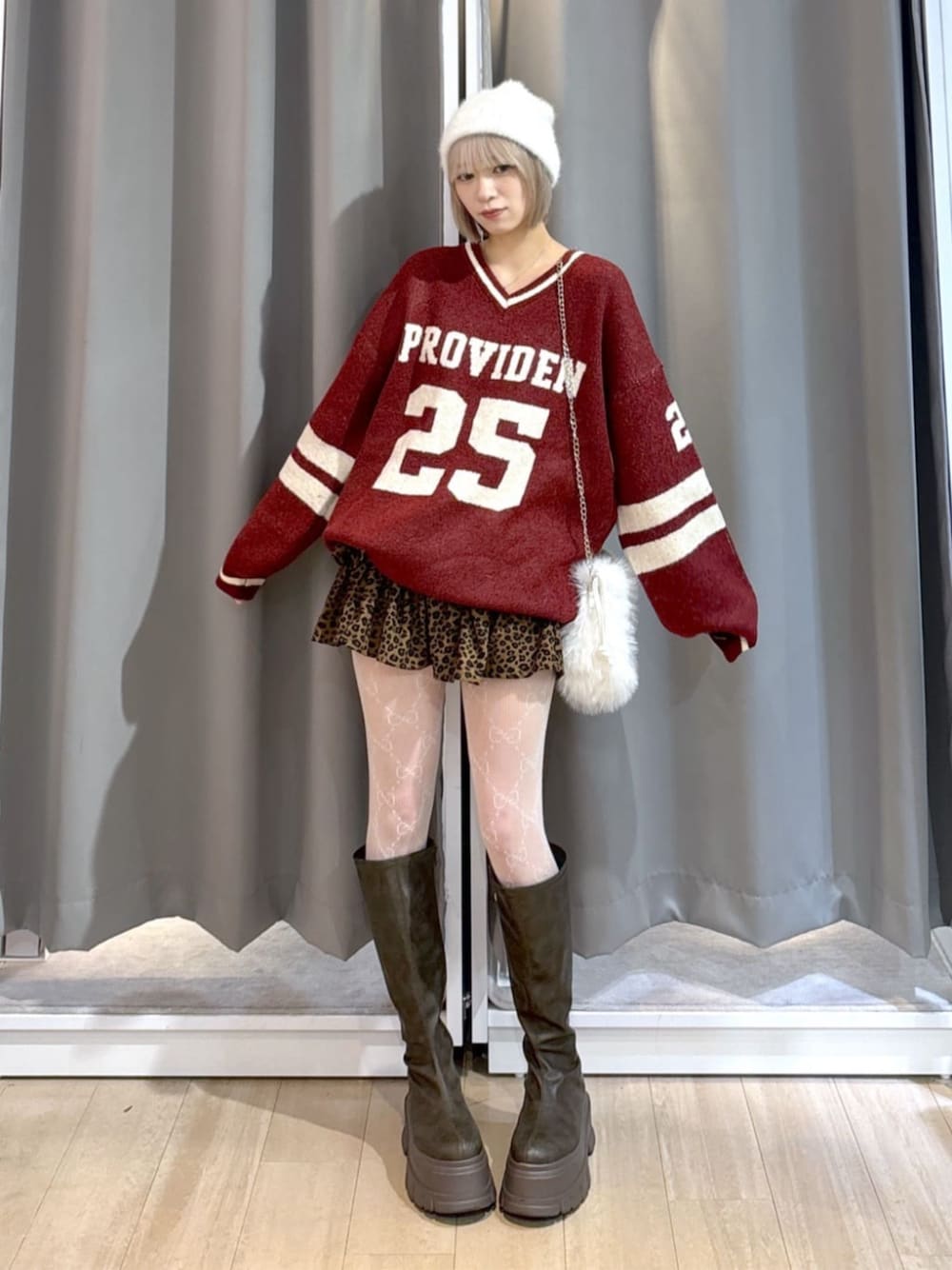 ブラウン系のブーツ、レッド系のニット/セーター、ホワイト系のショルダーバッグを着用したレディースの冬コーディネートの1枚目の写真