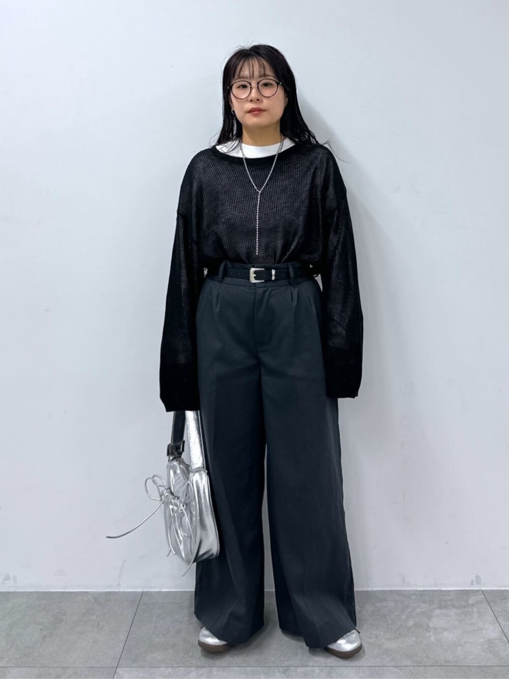 シルバー系のショルダーバッグ、ブラック系のニット/セーター、ホワイト系のTシャツ/カットソーを着用したレディースの秋コーディネートの1枚目の写真