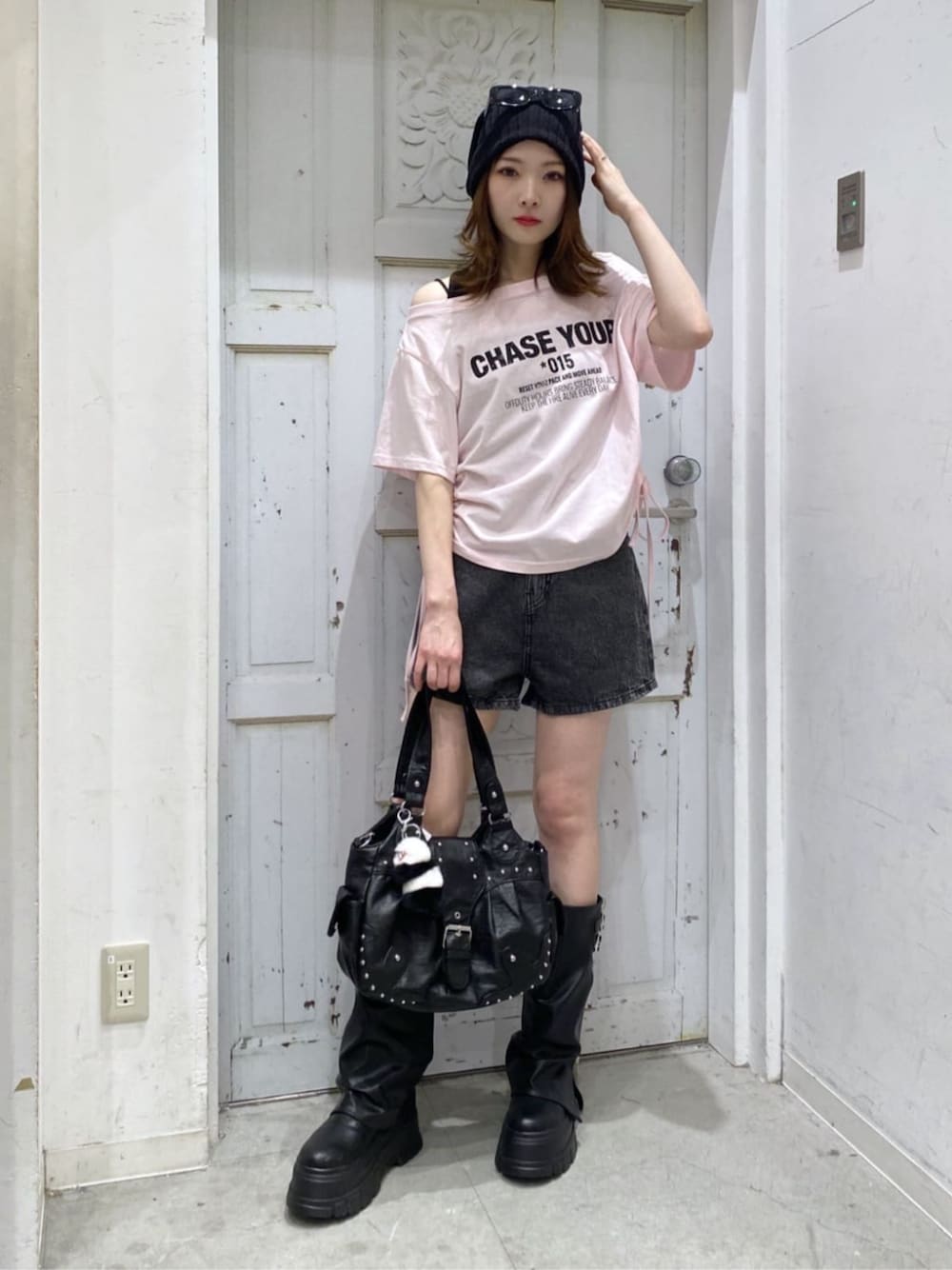 ブラック系のブーツ、ブラック系のデニムパンツ、ブラック系のハンドバッグを着用したレディースの夏コーディネートの1枚目の写真