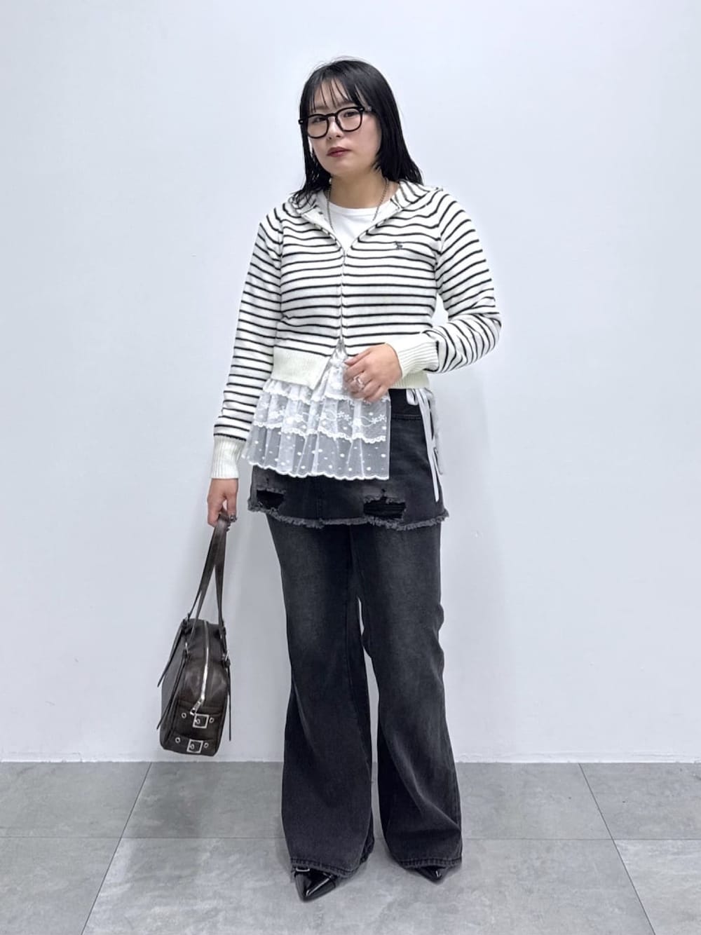 ブラック系のデニムパンツ、その他のスカート、ブラウン系のボストンバッグを着用したレディースの春コーディネートの1枚目の写真