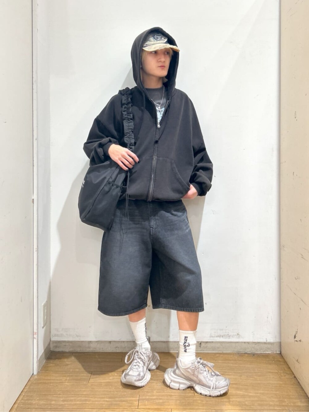 ブラック系のパーカー、ブラック系のショルダーバッグ、ブラック系のデニムパンツを着用したメンズの春コーディネートの1枚目の写真