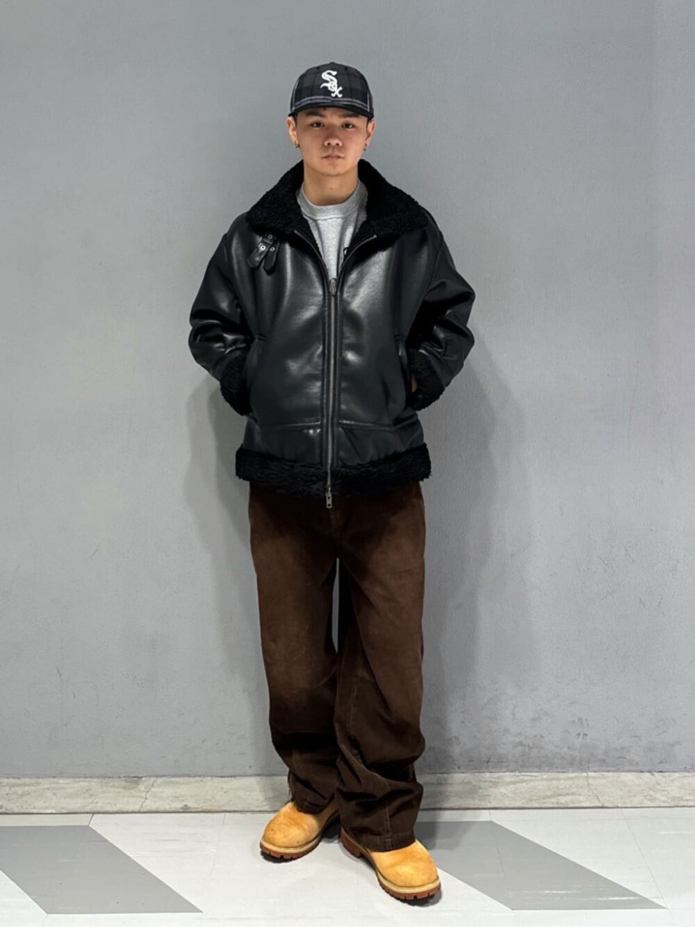 ブラウン系のチノパンツ、ブラック系のムートンコート、グレー系のスウェットを着用したメンズの冬コーディネートの1枚目の写真