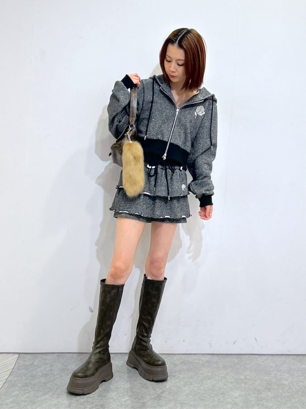 ブラウン系のブーツ、ブラック系のパーカー、ブラック系のスカートを着用したレディースの冬コーディネートの1枚目の写真