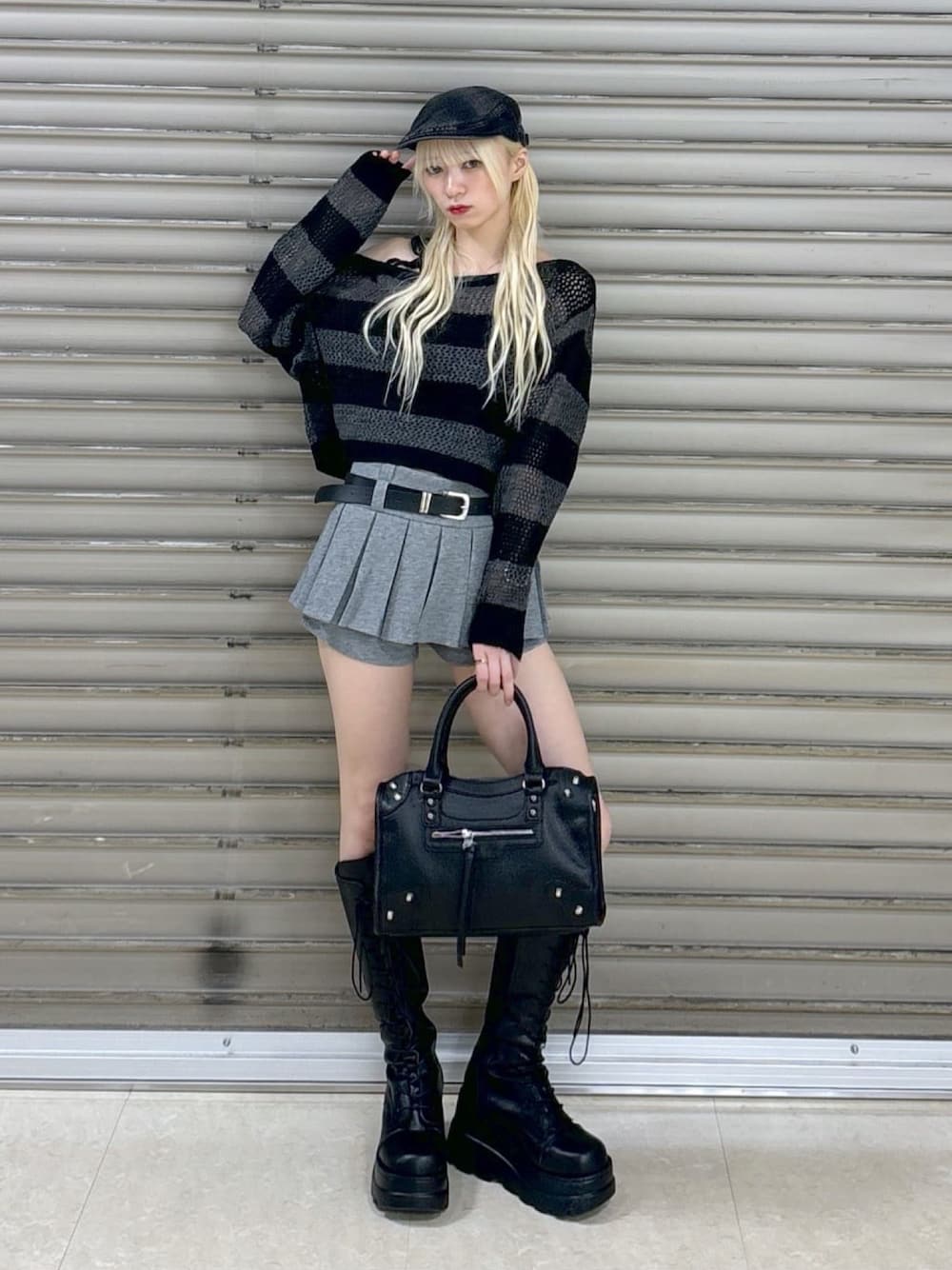 グレー系のニット/セーター、グレー系のスカート、ブラック系のボストンバッグを着用したレディースの秋コーディネートの1枚目の写真