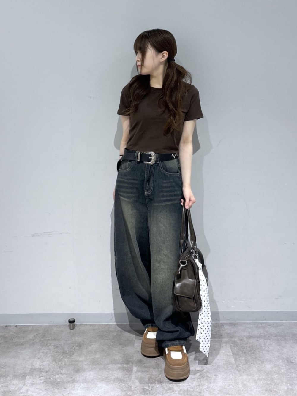 ブラウン系のショルダーバッグ、ブルー系のデニムパンツ、ブラウン系のスニーカーを着用したレディースの夏コーディネートの1枚目の写真