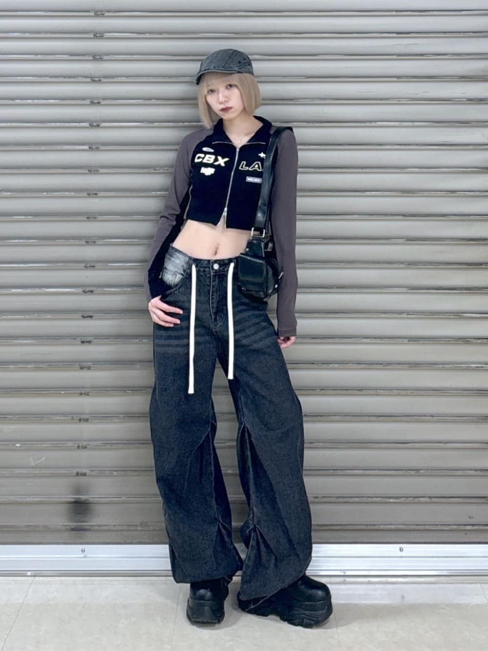 ブラック系のショルダーバッグ、ブラック系のデニムパンツ、ブラック系のブーツを着用したレディースの冬コーディネートの1枚目の写真