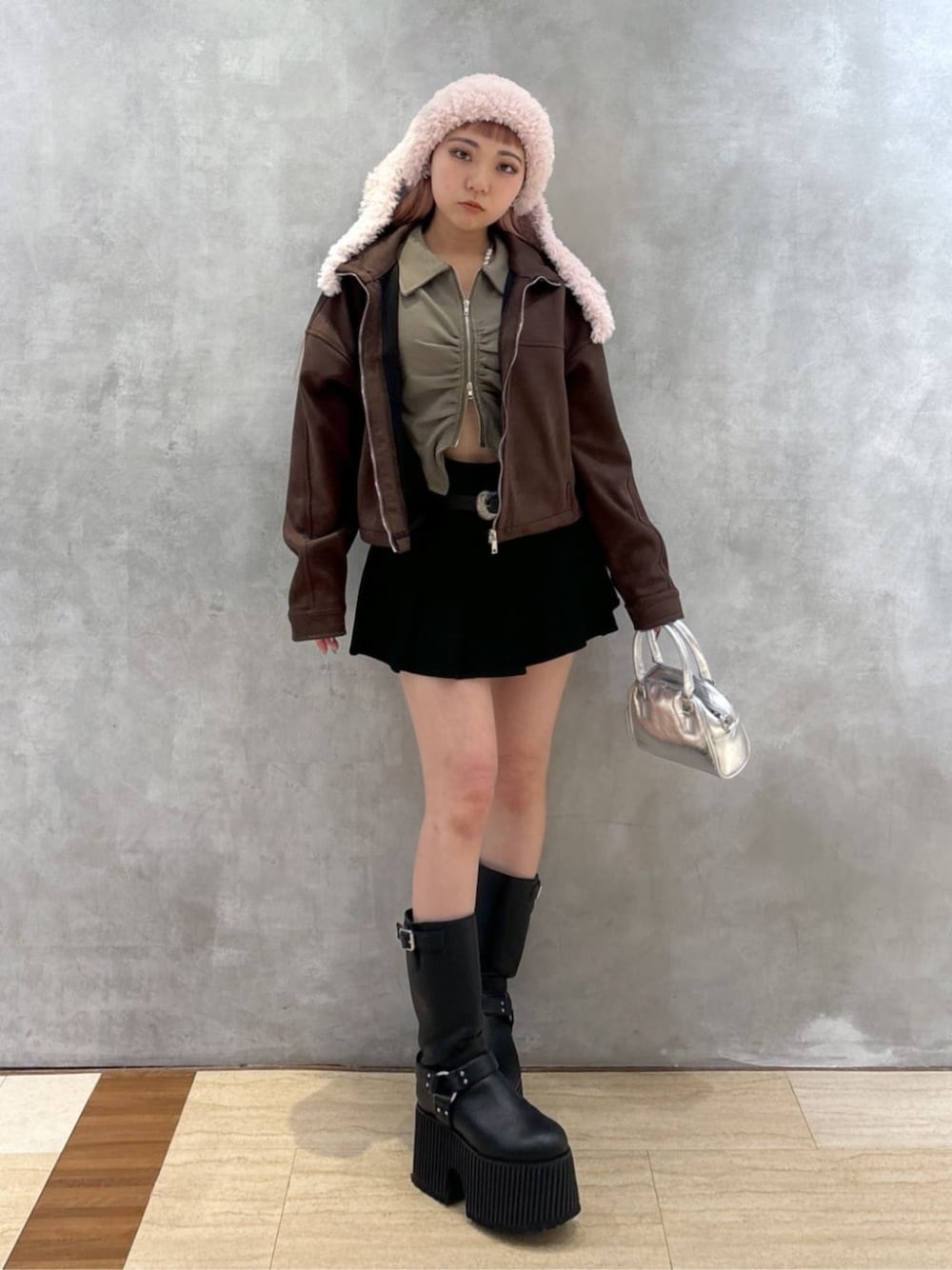 シルバー系のショルダーバッグ、グリーン系のTシャツ/カットソー、ブラウン系のブルゾンを着用したレディースの冬コーディネートの1枚目の写真